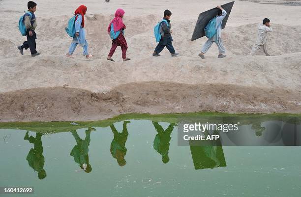 Afghan school children walk home after classes near an open classroom in the outskirts of Jalalabad on January 30, 2013. Afghanistan has had only...