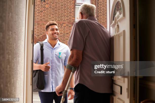 männliche bezirkskrankenschwester zu besuch bei patienten - client carer stock-fotos und bilder