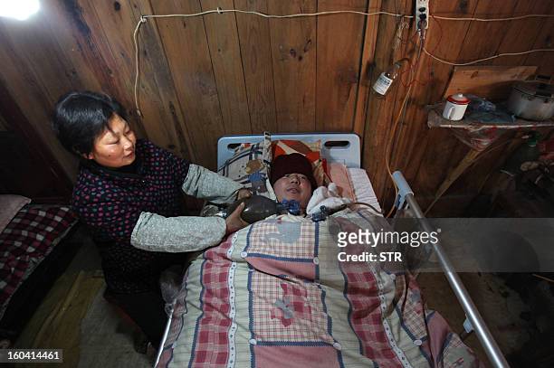This picture taken on January 28, 2013 shows Wang Lanqin compressing a PVC resuscitator pump to help her son Fu Xuepeng, a former mechanic who was...
