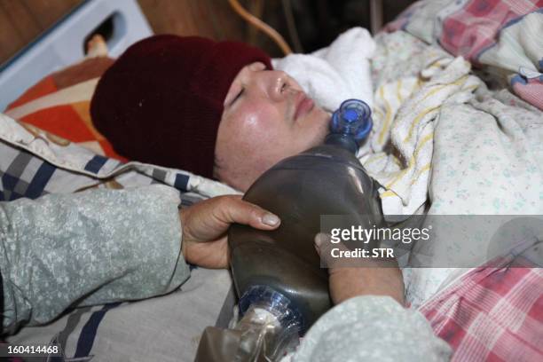 This picture taken on January 28, 2013 shows Wang Lanqin compressing a PVC resuscitator pump to help her son Fu Xuepeng, a former mechanic who was...