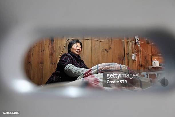 This picture taken on January 28, 2013 shows Wang Lanqin attending to her son Fu Xuepeng , a former mechanic who was paralyzed in a road accident...