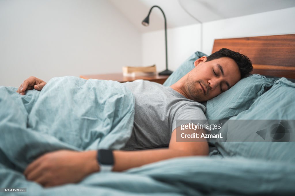 Biracial Man Sleeping in Bed With Watch