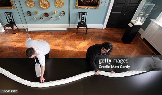 Artist Joan Sallas and Frohmut Zscheckel put the finishing touches to a 3 metre folded linen snake they are displaying as part of a new exhibition...