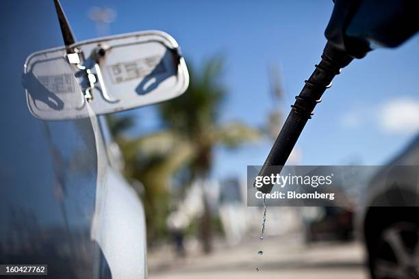 Gasoline drops from the end of the nozzle as an attendant finishes filling the tank of a vehicle at a Petroleo Brasileiro SA station in Rio de...