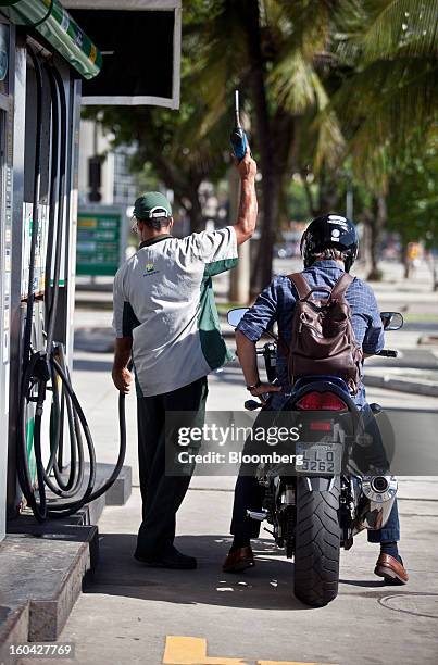 An attendant prepares to fill the tank of a motorcycle at a Petroleo Brasileiro SA station in Rio de Janeiro, Brazil, on Thursday, Jan. 31, 2013....