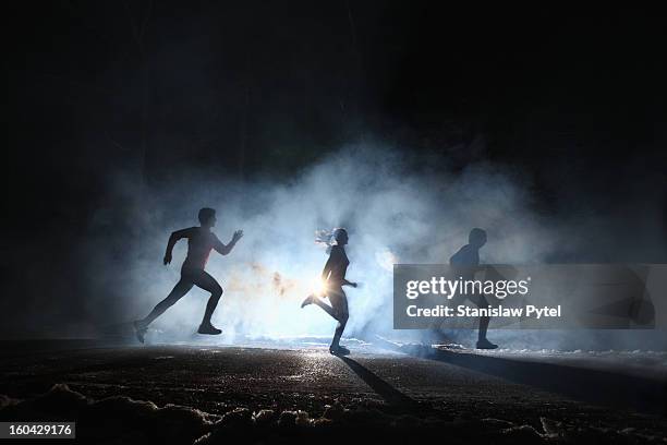 three runners on foggy road at night - passion stock pictures, royalty-free photos & images