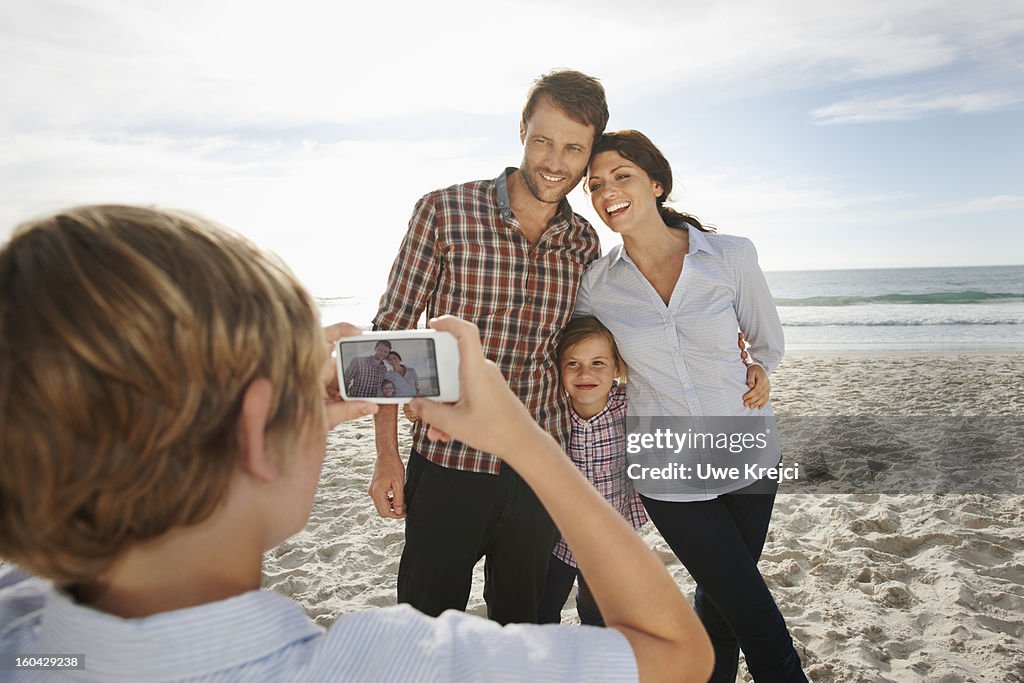 Boy (8-10) taking picture of his family, outdoors