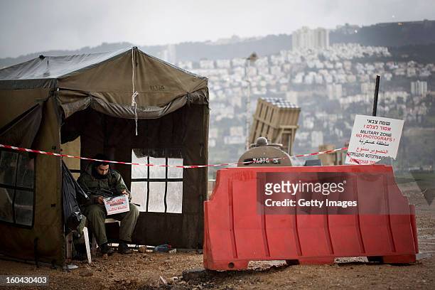 An Israeli soldier reads the newspaper next to an 'Iron Dome' short-range missile defense system on January 31, 2013 near the northern city of Haifa,...