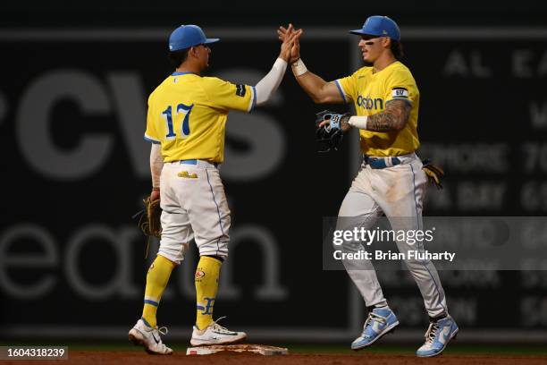 Jarren Duran of the Boston Red Sox high fives Luis Urias after a game against the Kansas City Royals at Fenway Park on August 09, 2023 in Boston,...