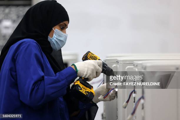 Saudi woman assembles air conditioning units at a factory in Dammam, in Saudi Arabia's eastern province on August 15, 2023.