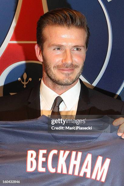 International soccer player David Beckham poses with his PSG Football shirt after his PSG signing at Parc des Princes on January 31, 2013 in Paris,...