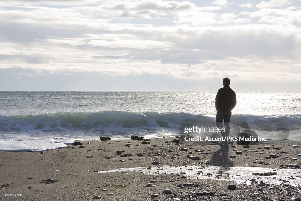 Man walking along a beach by the sea