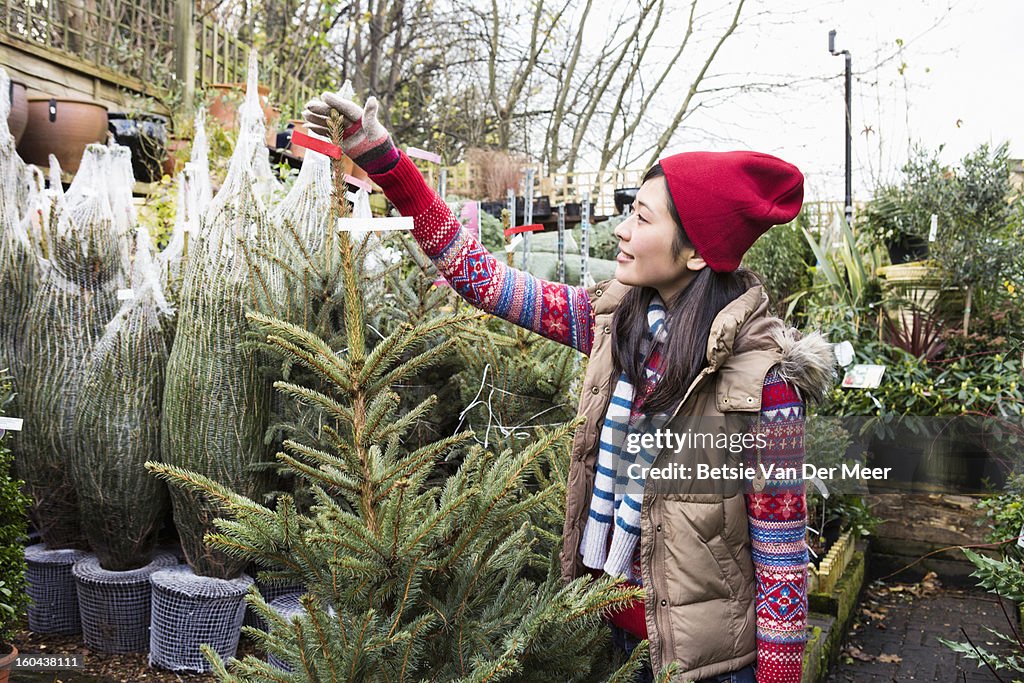 Woman choosing christmastree in gardencentre.