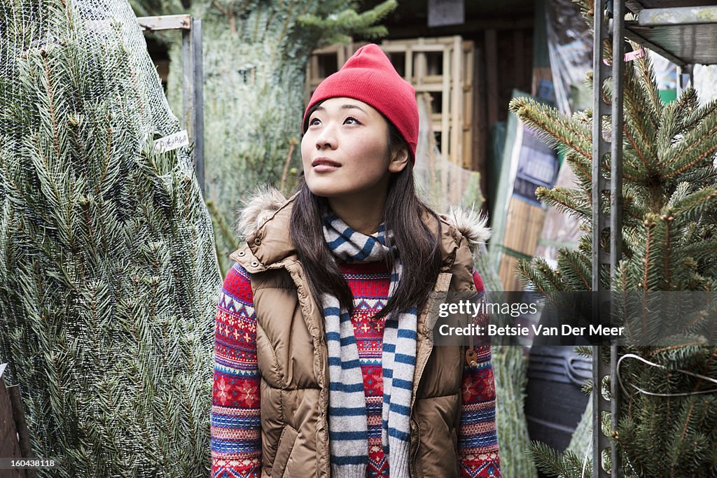 Woman looking for christmastree in gardencentre.