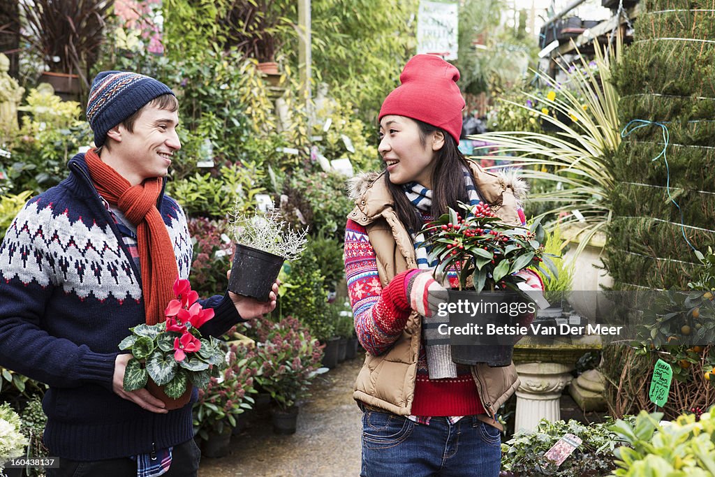 Couple choosing plants in garden centre..