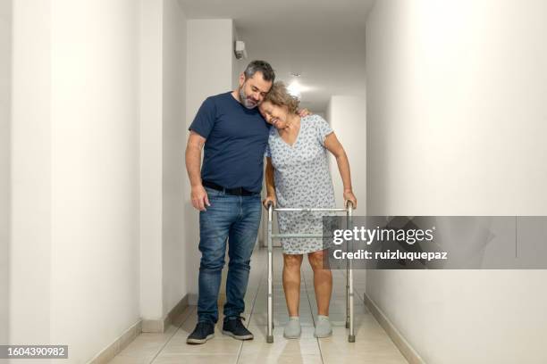 elderly woman with a disability and a walker assisted by a physiotherapist in the hospital - hip replacement stock pictures, royalty-free photos & images