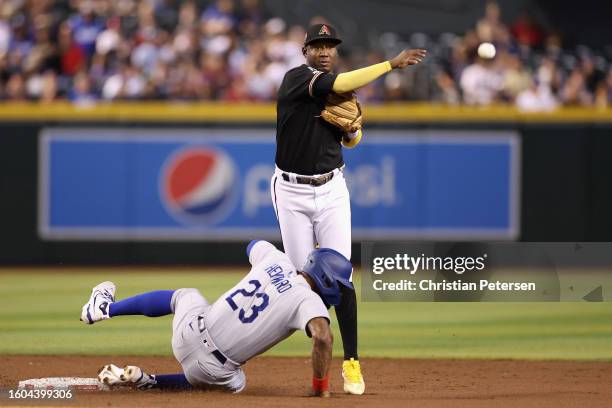 Infielder Geraldo Perdomo of the Arizona Diamondbacks throws over Jason Heyward of the Los Angeles Dodgers to complete a double play during the third...