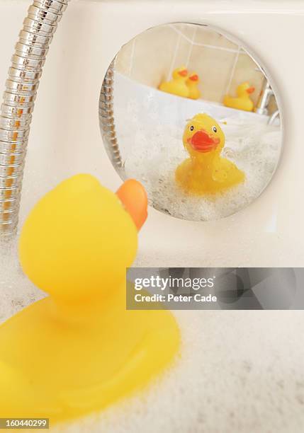 rubber ducks in bath looking at reflection - badeend stockfoto's en -beelden