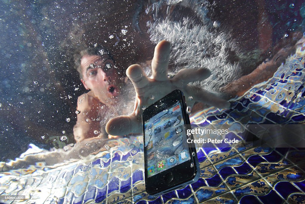 Smart phone being dropped into swimming pool
