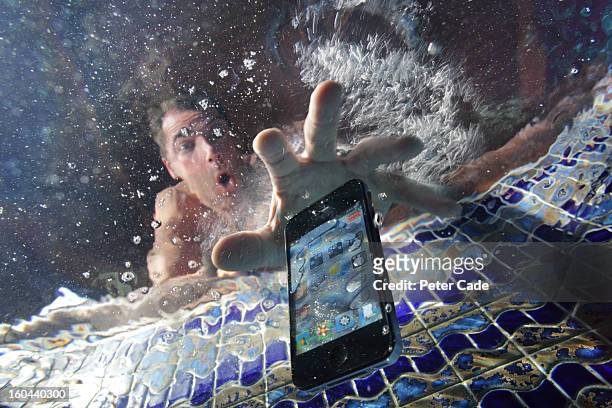 smart phone being dropped into swimming pool - water fall stockfoto's en -beelden