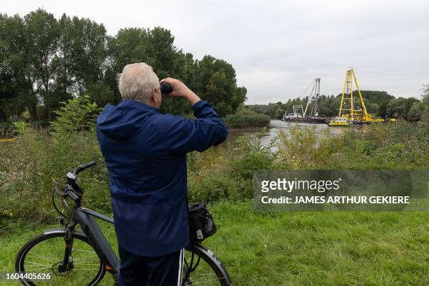 Spectator looks at the scene of the salvaging works to bring the Dutch barge that sunk last week on the Schelde river to the surface, in Grembergen...