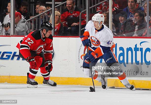 David Ullstrom of the New York Islanders plays the puck while being defended by Krystofer Barch of the New Jersey Devils during the game at the...