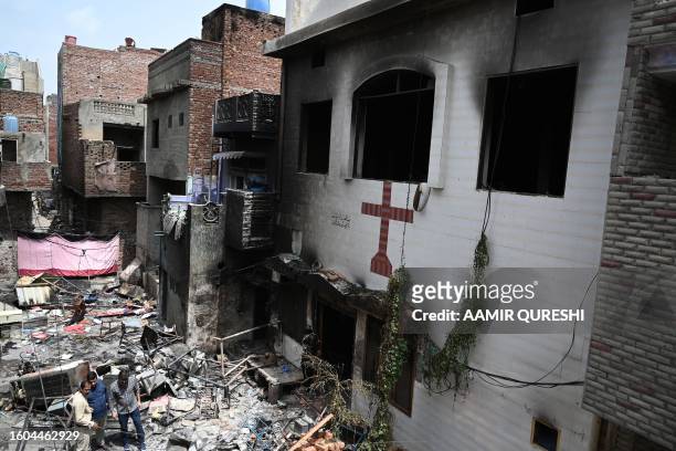 Men stand amid debris outside the torched Saint John Church in Jaranwala on the outskirts of Faisalabad on August 17 a day after an attack by Muslim...