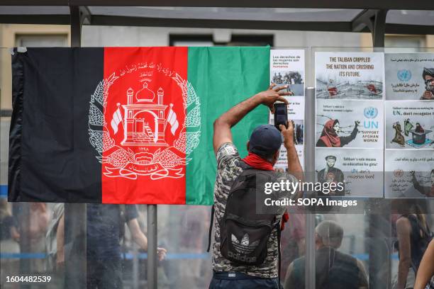 Man takes photographs of the placards and the Afghan flag during the demonstration in Madrid against the abuses of the Taliban regime. A...