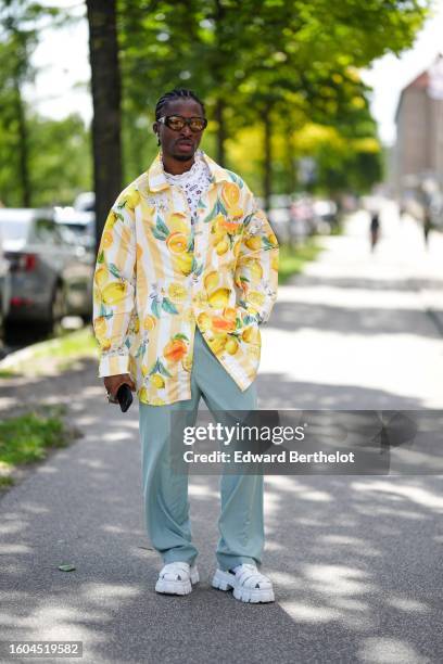 Guest wears black sunglasses, a white cut-out pattern high neck blouse, a pale yellow and green lemon print pattern oversized shirt, pale green suit...