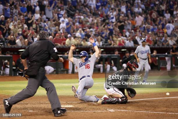 Will Smith of the Los Angeles Dodgers slides into home plate to score a run past catcher Jose Herrera of the Arizona Diamondbacks during the eighth...
