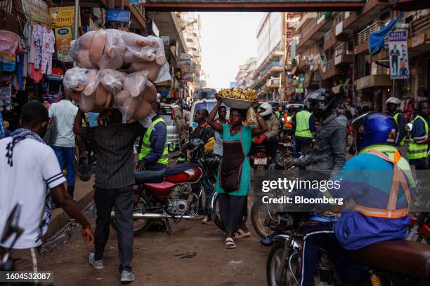 Street vendors carry goods past moto taxis on a retail street in central Kampala, Uganda, on Wednesday, Aug. 16, 2023. Uganda's central bank said it...