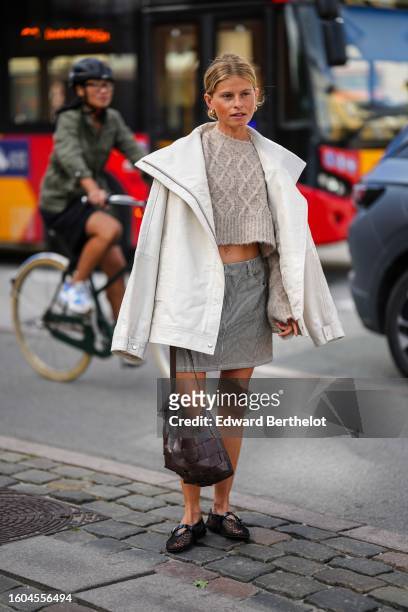 Guest wears gold earrings, a beige braided wool embossed checkered pattern cropped pullover, a white rain coat, a black and white micro striped print...