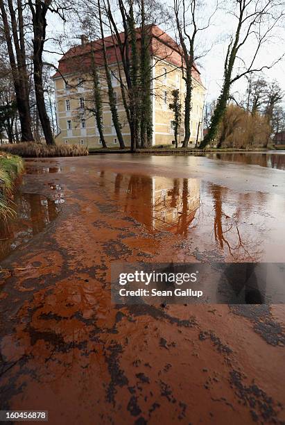 Iron-rich sludge lies on top of thawing ice in the ponds that are fed by a nearby creek next to Schloss Vetschau palace on January 31, 2013 in...