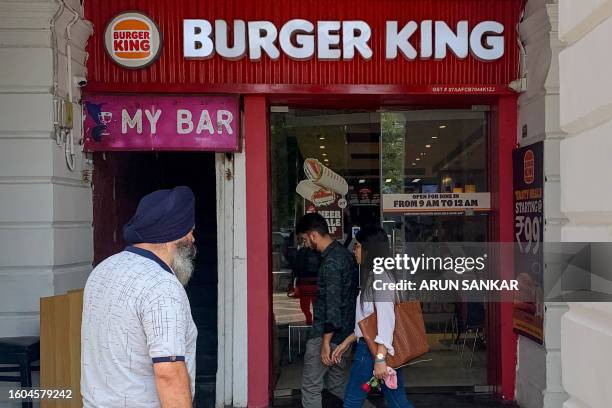 People walk past a Burger King outlet in New Delhi on August 17, 2023. Soaring vegetable prices after a bad harvest have prompted Burger King's...