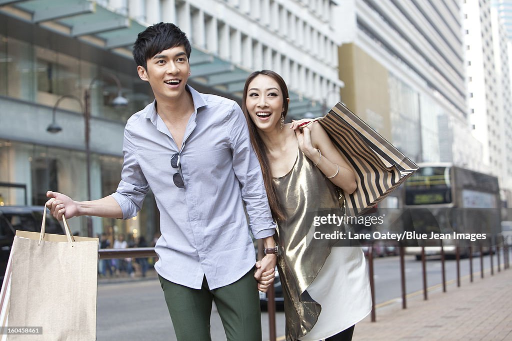 Cheerful young couple with shopping bags walking in the street, Hong Kong