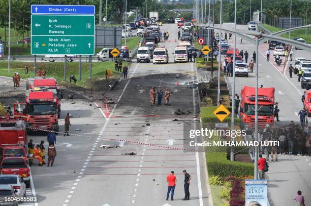 Members of the fire and rescue department inspect the crash site of a plane on a street in Shah Alam, Malaysia's Selangor state on August 17, 2023. A...