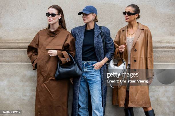 Annabel Rosendahl wears brown coat, black bag & Tine Andrea wears cap, grey oversized coat, denim jeans & Darja Barannik wears brown coat, white...