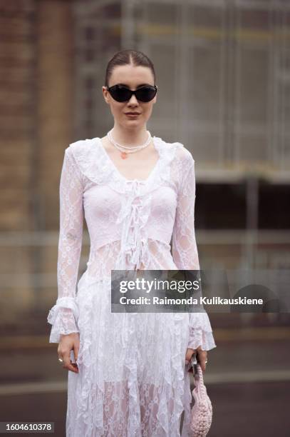 Guest wears a white sheer dress, white tights, sunglasses, and a white bag outside OperaSport during the Copenhagen Fashion Week Spring/Summer 2024...