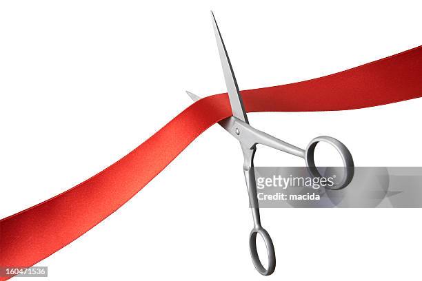 pair of scissors cutting a red ribbon - cutting stockfoto's en -beelden