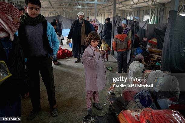 Girl stands with bags and blankets as new Syrian refugees arrive at the International Organization for Migration at the Za'atari refugee camp on...
