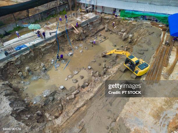 aerial view a construction site excavator is helping to lift steel for workers to assemble into the construction foundation. - väg och vattenbyggnadsingenjör bildbanksfoton och bilder