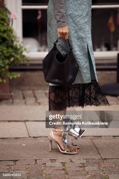 Renia Jaz wears a turtle neck grey top, silk teal and black dress and silver shoes outside Baum and Pferdgarten during the Copenhagen Fashion Week...