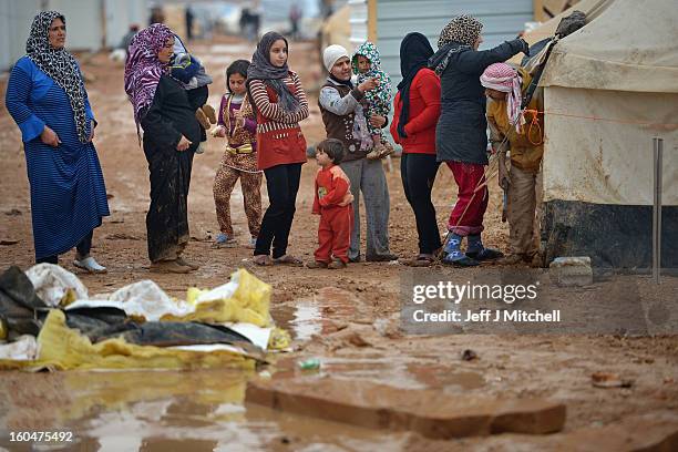 Women stop to watch a tent being erected as Syrian refugees go about their daily business in the Za’atari refugee camp on February 1, 2013 in...