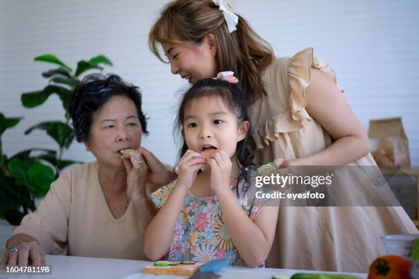 grandmother, mother and granddaughter prepare food in the kitchen. - girl making sandwich stock pictures, royalty-free photos & images