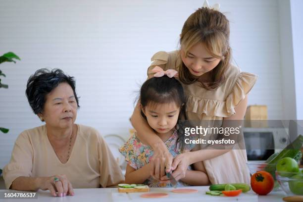 grandmother, mother and granddaughter prepare food in the kitchen. - girl making sandwich stock pictures, royalty-free photos & images