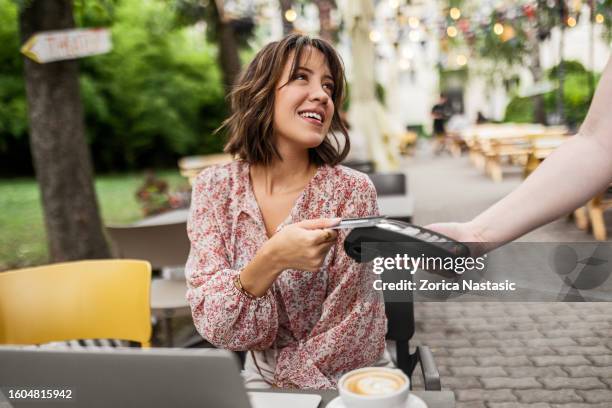 sie bezahlt ihre rechnung mit einer karte im café. - kontaktlos bezahlen stock-fotos und bilder