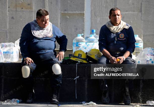 Firefighters take a rest during works at the premises of the building that houses state-owned Mexican oil giant Pemex following a blast on the eve,...