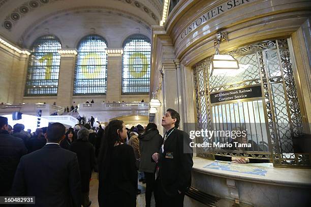 People stand near a ticket window in Grand Central Terminal beneath a '100' sign during centennial celebrations on the day the famed Manhattan...