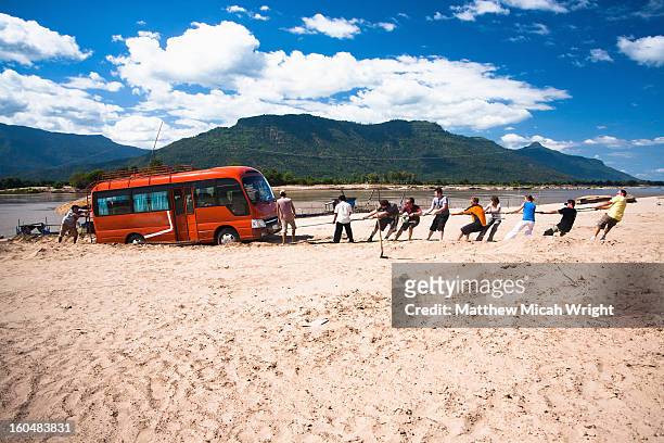 people pulling out a bus stuck in sand - to pull together stock pictures, royalty-free photos & images