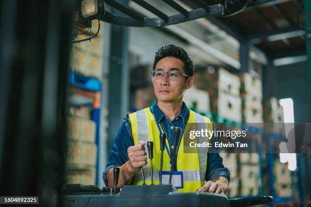 asian chinese warehouse worker operating forklift loading carton pallet boxes for shipment - south east asian people stock pictures, royalty-free photos & images